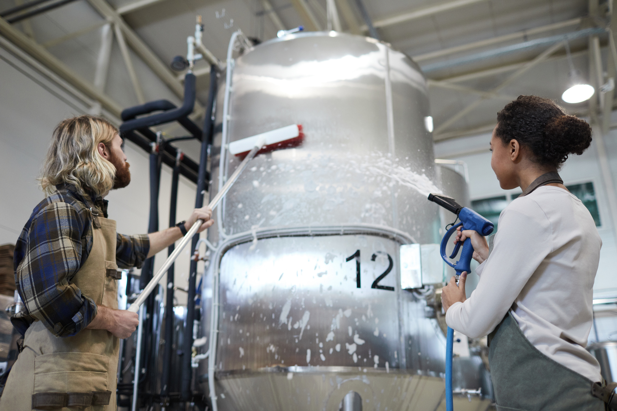 Two Workers Cleaning Machines at Factory